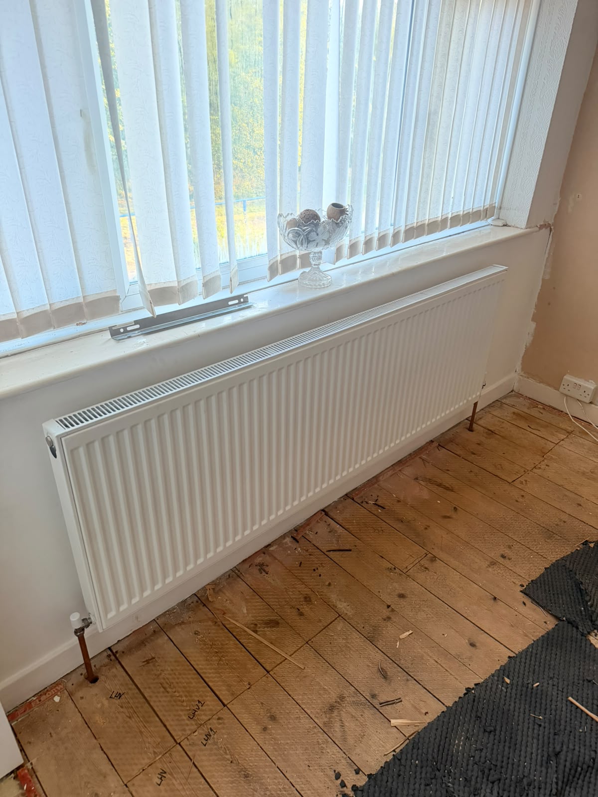 New white double-panel radiator fitted under bay window during central heating upgrade
