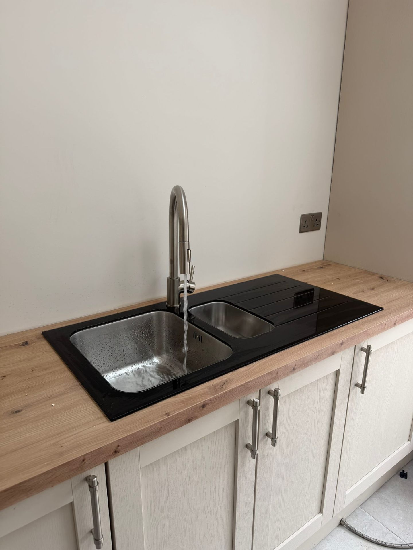 Black glass inset 1.5 bowl kitchen sink with brushed steel pull-out mixer tap on oak worktop, Coventry