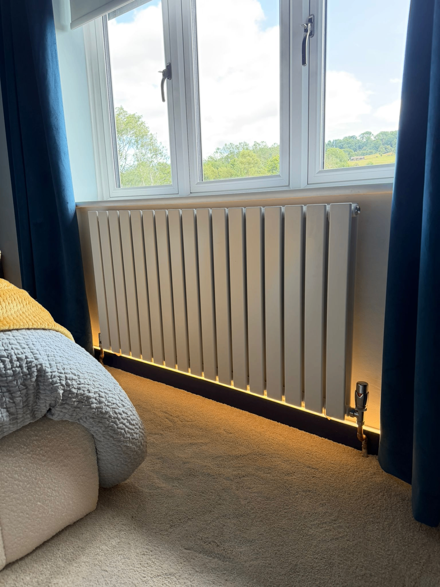 White vertical flat-panel designer radiator with chrome TRV fitted under bedroom window, Coventry