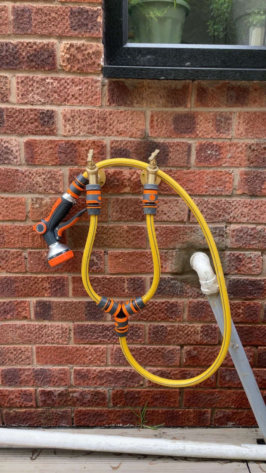 Twin outside garden taps with brass valves fitted to brick wall