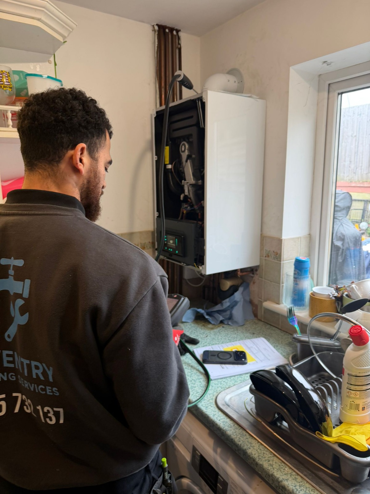 Engineer servicing a combi boiler in kitchen