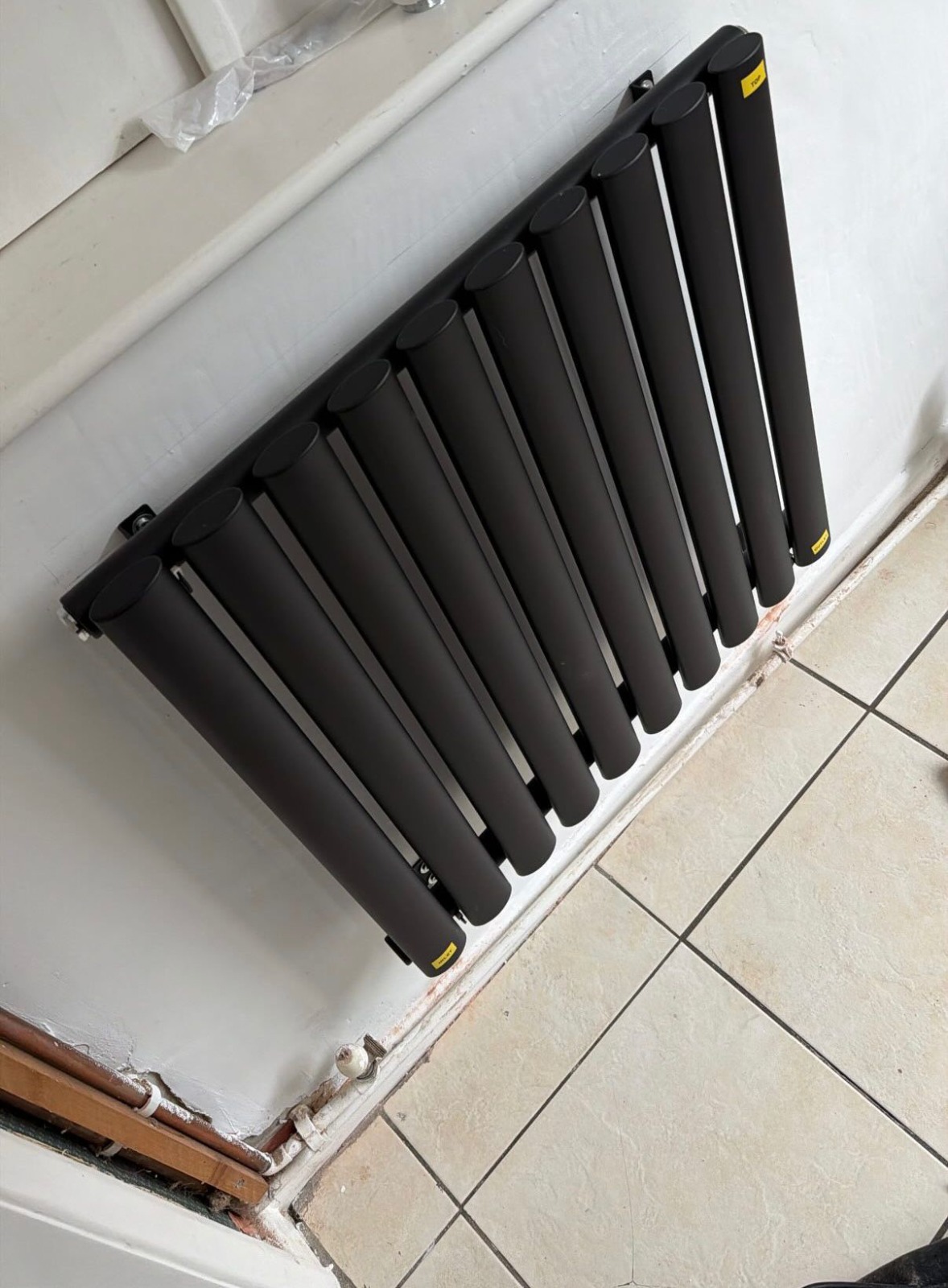 Designer black column radiator fitted in hallway