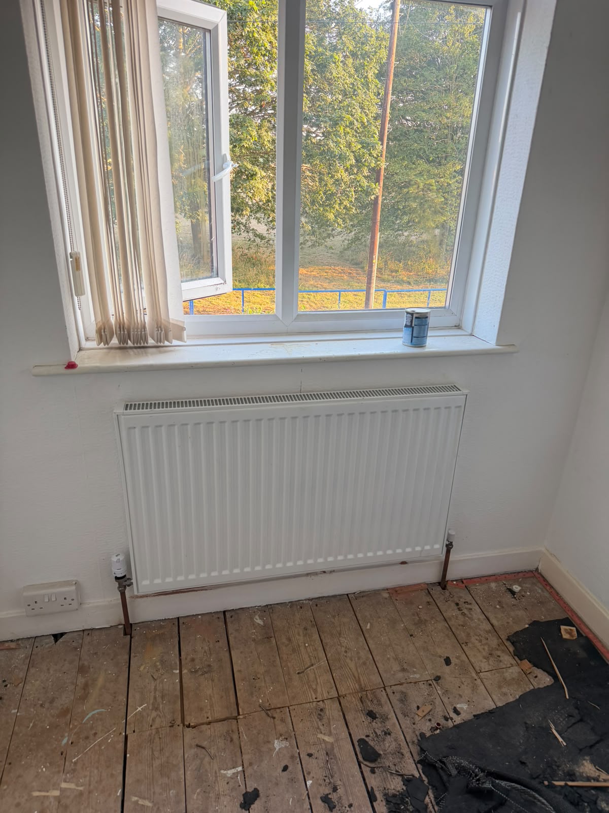 White compact radiator installed under window with fresh copper tails and TRV